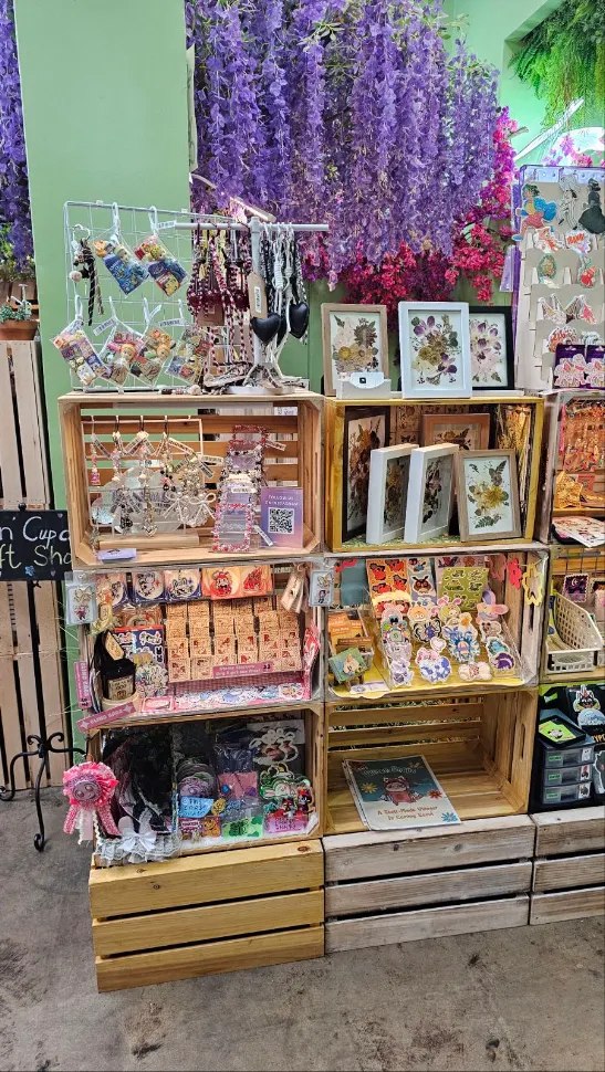 Jewelry and framed botanical art beneath purple flowers at Happy Humble Hub