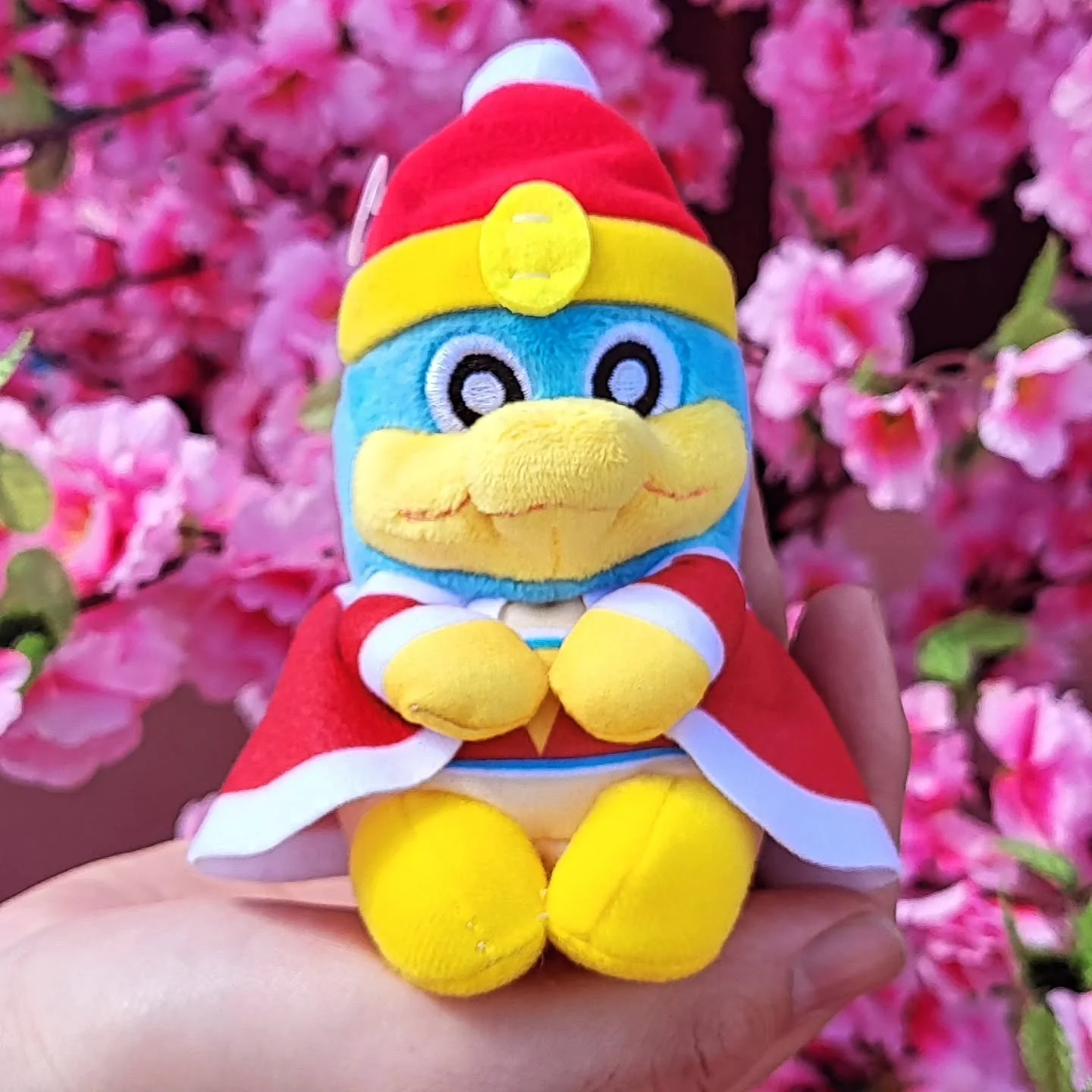 King Dedede plush toy in front of pink cherry blossoms